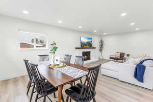 Dining area featuring a stone fireplace, light wood finished floors, and recessed lighting
