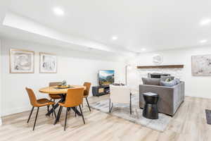 Dining room featuring light wood-style flooring, a stone fireplace, and recessed lighting