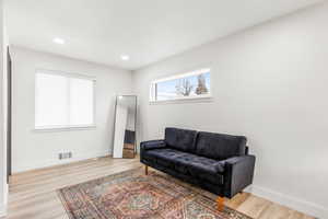 Living area with light wood-type flooring and recessed lighting