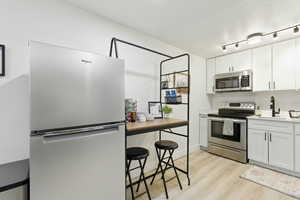 Kitchen featuring appliances with stainless steel finishes, white cabinetry, and light wood-style floors
