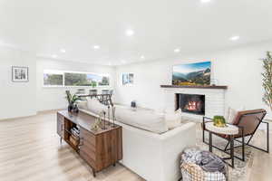 Living room featuring a fireplace, recessed lighting, and light wood-style flooring