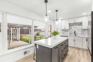 Kitchen featuring white cabinetry, a kitchen breakfast bar, decorative light fixtures, light wood-type flooring, and recessed lighting
