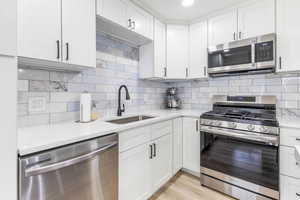 Kitchen featuring appliances with stainless steel finishes, white cabinets, and backsplash