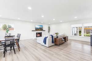 Living room with a brick fireplace, light wood-style floors, and recessed lighting