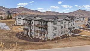 View of front facade with a mountain view, stone siding, and a balcony