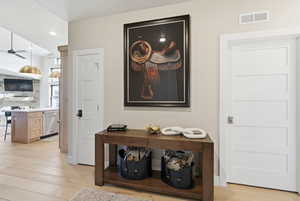 Hallway with light wood-style floors and recessed lighting