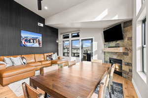 Dining space featuring an accent wall, a fireplace, light wood-style flooring, vaulted ceiling, and recessed lighting