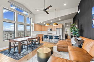 Living room featuring a ceiling fan, light wood-type flooring, recessed lighting, high vaulted ceiling, and an accent wall