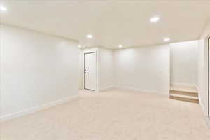 Finished basement with recessed lighting and light colored carpet