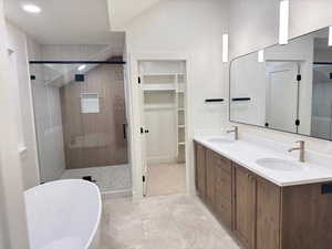 Full bathroom featuring a freestanding tub, double vanity, a stall shower, a spacious closet, and a textured ceiling