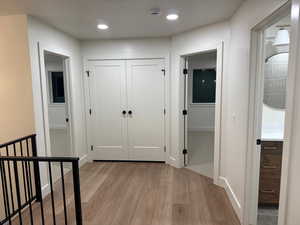 Hall with light wood-type flooring and recessed lighting