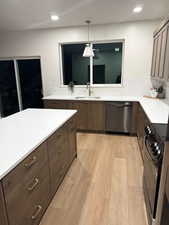 Kitchen with dark brown cabinets, black electric range oven, dishwasher, light wood-style floors, and light stone countertops
