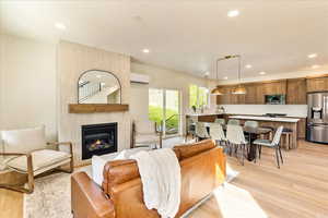 Living area with light wood-type flooring, a large fireplace, and recessed lighting