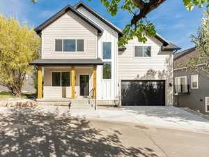 View of front facade featuring a porch, board and batten siding, concrete driveway, and a garage