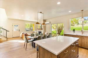 Kitchen featuring wood finish cabinets, a kitchen island, open floor plan, decorative light fixtures, and a breakfast bar