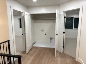 Laundry area featuring light wood-style floors, hookup for a washing machine, light colored carpet, and electric dryer hookup