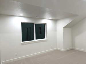 Carpeted spare room with a textured ceiling and recessed lighting