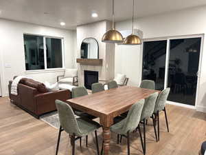 Dining area with a large fireplace, light wood-type flooring, and recessed lighting