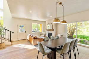 Dining space with a textured ceiling, light wood-style floors, a fireplace, and recessed lighting