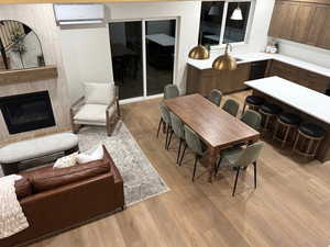 Dining space featuring light wood-style flooring, a large fireplace, and an AC wall unit