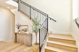 Staircase with wood finished floors and a high ceiling