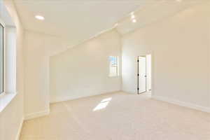 Spare room featuring light carpet, recessed lighting, and lofted ceiling