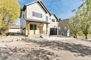 View of front of home with covered porch, an attached garage, and driveway