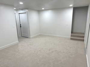Basement with a textured ceiling, light carpet, and recessed lighting