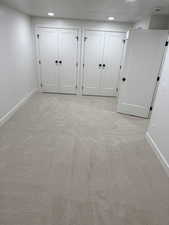 Unfurnished bedroom with two closets, light colored carpet, and recessed lighting