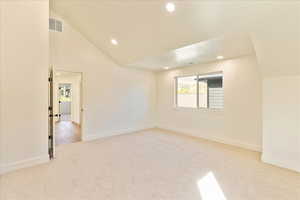 Spare room with light carpet, lofted ceiling, and recessed lighting