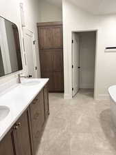 Full bath with double vanity, a freestanding bath, and lofted ceiling