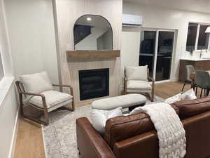 Living room with light wood finished floors, a fireplace, and a wall mounted AC