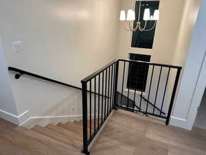 Staircase featuring a chandelier and wood finished floors