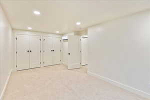 Unfurnished bedroom with two closets, light colored carpet, and recessed lighting