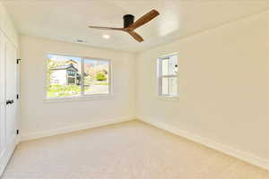 Unfurnished room featuring light colored carpet, ceiling fan, and plenty of natural light