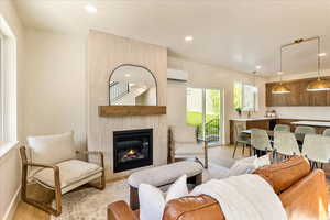 Living area with a fireplace, light wood-type flooring, and recessed lighting