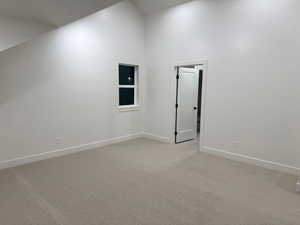 Empty room featuring high vaulted ceiling and light colored carpet