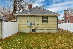 Rear view of house featuring a fenced backyard, a chimney, and a shingled roof