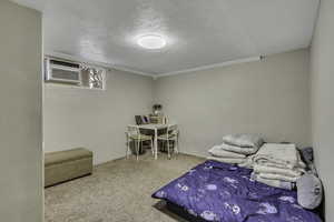 Carpeted bedroom featuring a textured ceiling and an AC wall unit