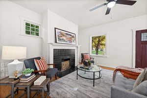 Living room with a fireplace, wood finished floors, and a ceiling fan