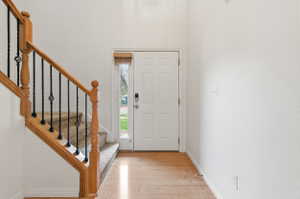 Foyer with light wood-style floors, stairway, and a high ceiling