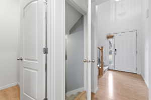 Entryway featuring stairs, light wood-style floors, and a high ceiling