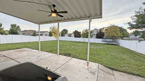 Fenced backyard with a ceiling fan, a patio area, and a trampoline