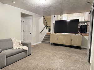 Living room with light carpet, a textured ceiling, stairway, and ornamental molding