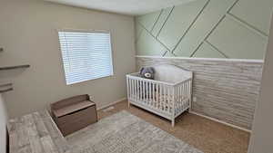 Carpeted bedroom with a crib and baseboards