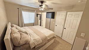 Carpeted bedroom featuring ceiling fan and a textured ceiling