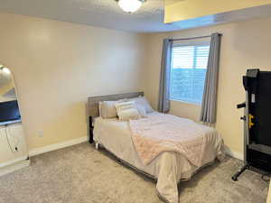 Carpeted bedroom with a textured ceiling and baseboards