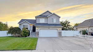 View of front of home with stucco siding, a garage, driveway, and stone siding