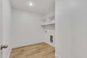 Laundry area featuring light wood-style flooring, hookup for a washing machine, and recessed lighting
