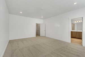 Unfurnished bedroom with light colored carpet, recessed lighting, and connected bathroom